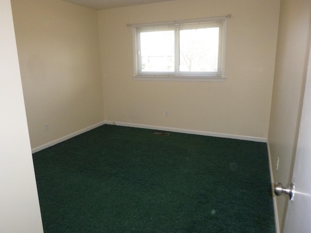 spare room with baseboards, visible vents, and dark carpet