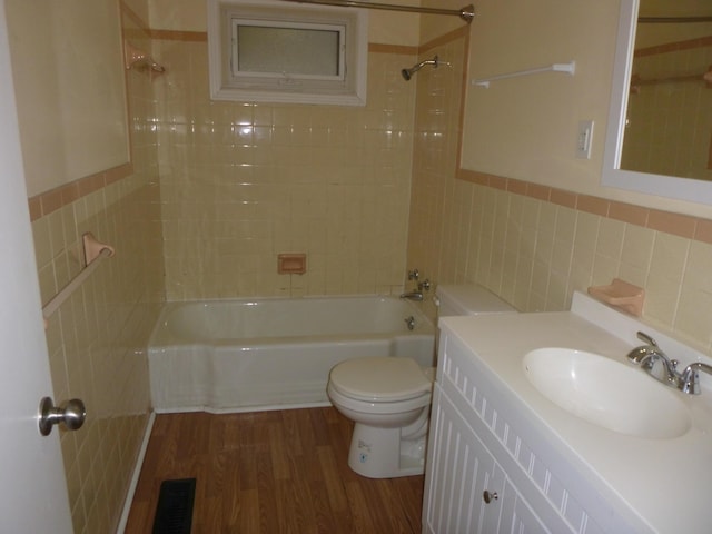 bathroom with visible vents, toilet, wood finished floors,  shower combination, and tile walls