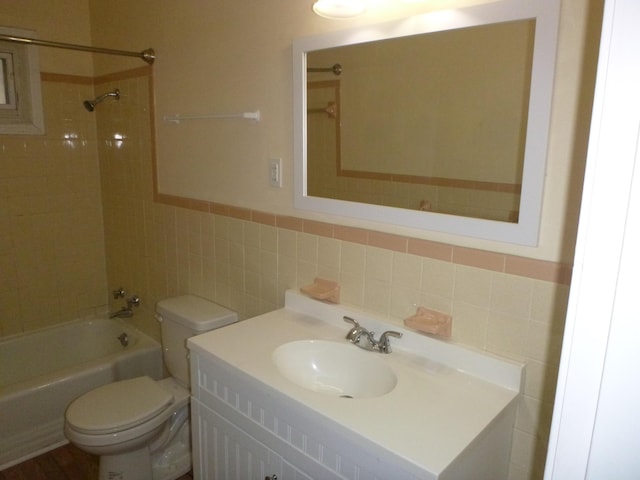 bathroom with toilet, a wainscoted wall, shower / bath combination, vanity, and tile walls