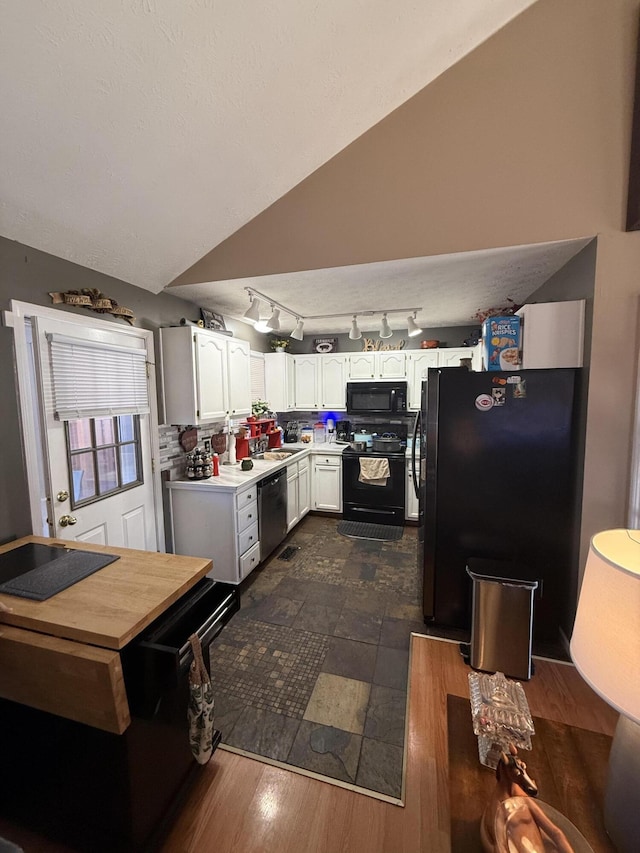 kitchen with lofted ceiling, light countertops, dark wood-type flooring, white cabinets, and black appliances