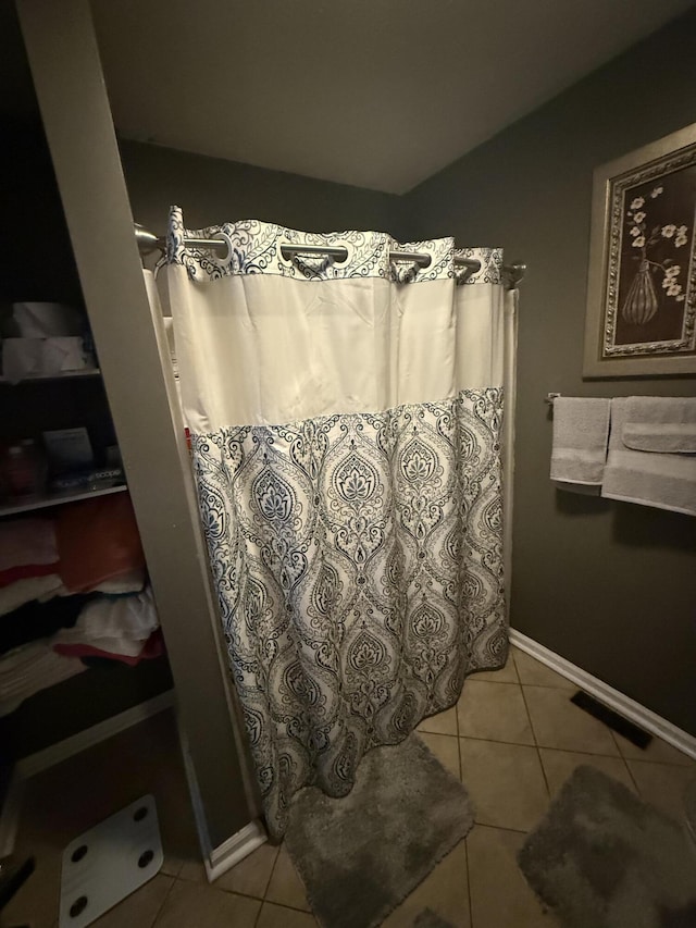 bathroom featuring a shower with shower curtain, tile patterned flooring, visible vents, and baseboards