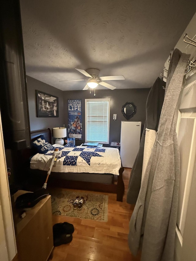 bedroom with a textured ceiling, ceiling fan, and wood finished floors