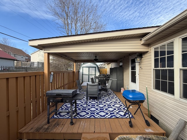 deck with a storage shed, outdoor dining space, fence, and an outdoor structure