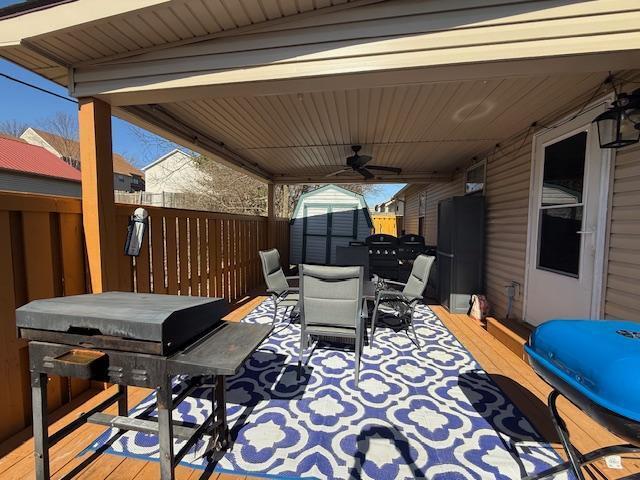 view of patio with an outbuilding, outdoor dining area, fence, a deck, and a shed