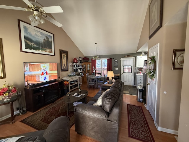 living room with lofted ceiling, ceiling fan, baseboards, and wood finished floors