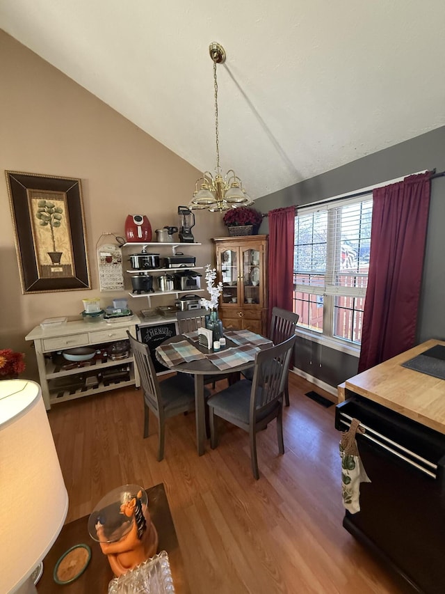 dining space featuring lofted ceiling, visible vents, an inviting chandelier, and wood finished floors