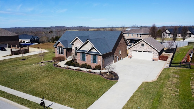 view of front of property featuring a front lawn, driveway, fence, an attached garage, and brick siding