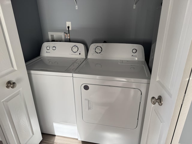 laundry room with laundry area, wood finished floors, and washing machine and clothes dryer