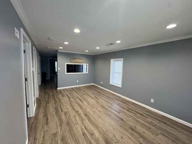 empty room featuring ornamental molding, visible vents, baseboards, and wood finished floors