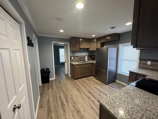 kitchen featuring ornamental molding, freestanding refrigerator, and dark brown cabinetry