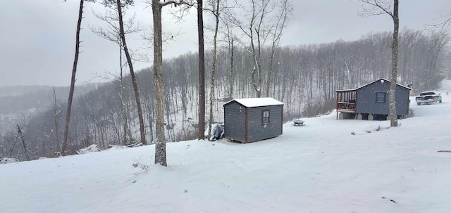 yard covered in snow with a garage and a view of trees