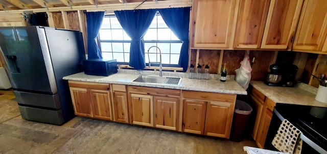 kitchen featuring brown cabinets, light stone countertops, stainless steel refrigerator with ice dispenser, and a sink