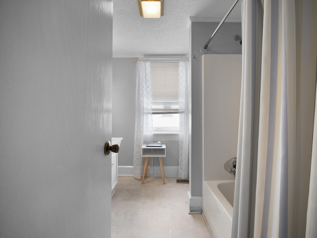 bathroom with a textured ceiling, shower / bathtub combination, visible vents, and baseboards