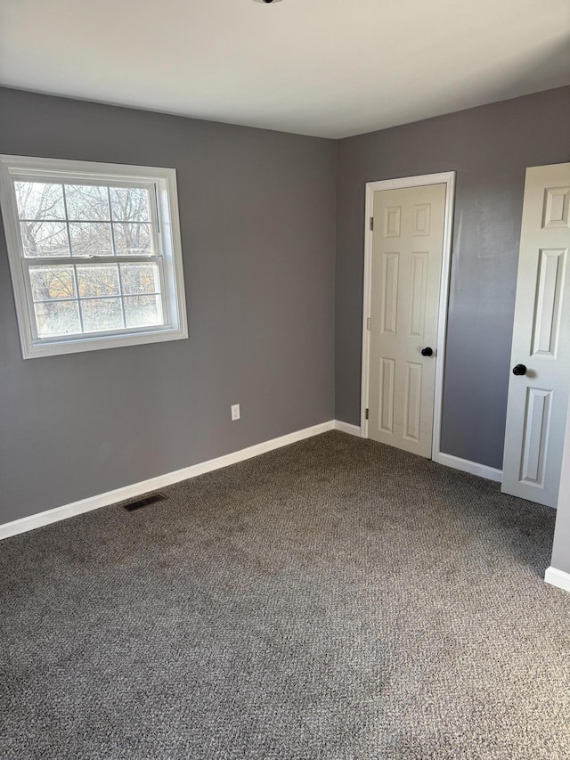 unfurnished room with carpet floors, visible vents, and baseboards