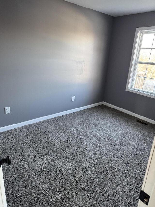 empty room with carpet floors, visible vents, and baseboards