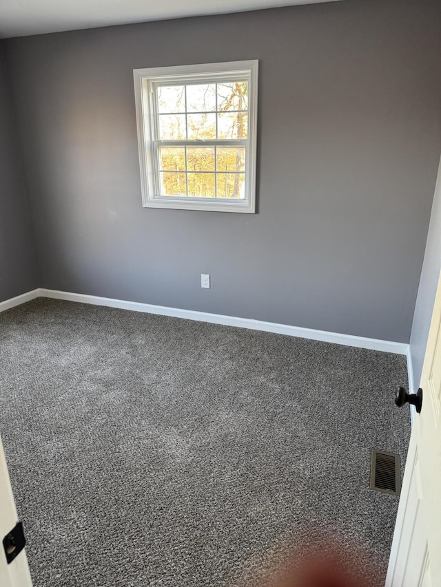 spare room featuring carpet floors, baseboards, and visible vents