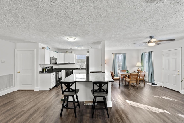 kitchen featuring a breakfast bar, a sink, visible vents, dishwasher, and stainless steel range with electric stovetop