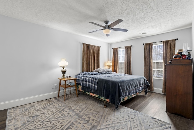 bedroom with visible vents, a ceiling fan, a textured ceiling, wood finished floors, and baseboards