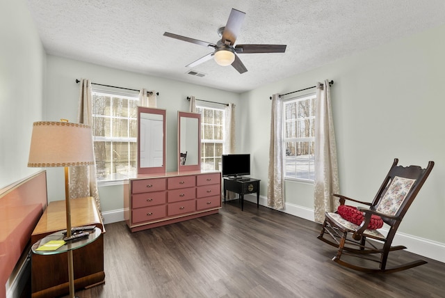 living area with baseboards, visible vents, a ceiling fan, dark wood-type flooring, and a textured ceiling