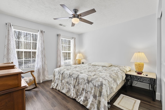 bedroom with dark wood-style floors, visible vents, a ceiling fan, a textured ceiling, and baseboards