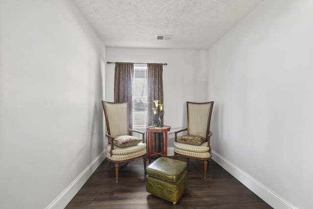 living area featuring visible vents, a textured ceiling, baseboards, and wood finished floors