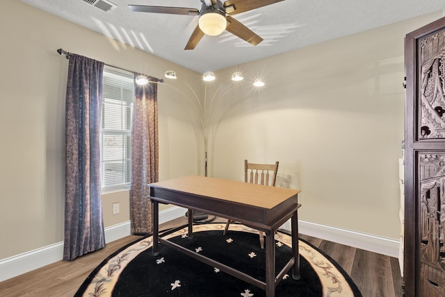 home office featuring a ceiling fan, a textured ceiling, baseboards, and wood finished floors