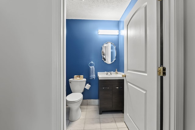 bathroom featuring a textured ceiling, tile patterned flooring, toilet, vanity, and baseboards