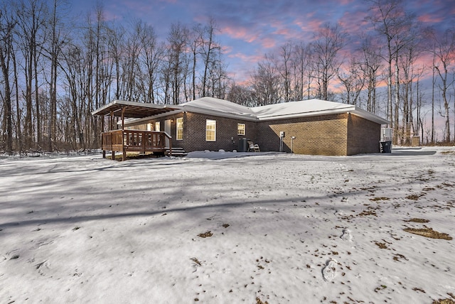 view of snow covered exterior featuring a garage and brick siding