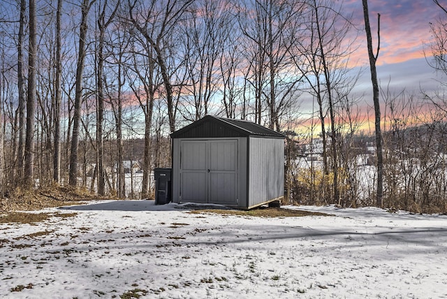 snow covered structure with an outbuilding and a storage unit