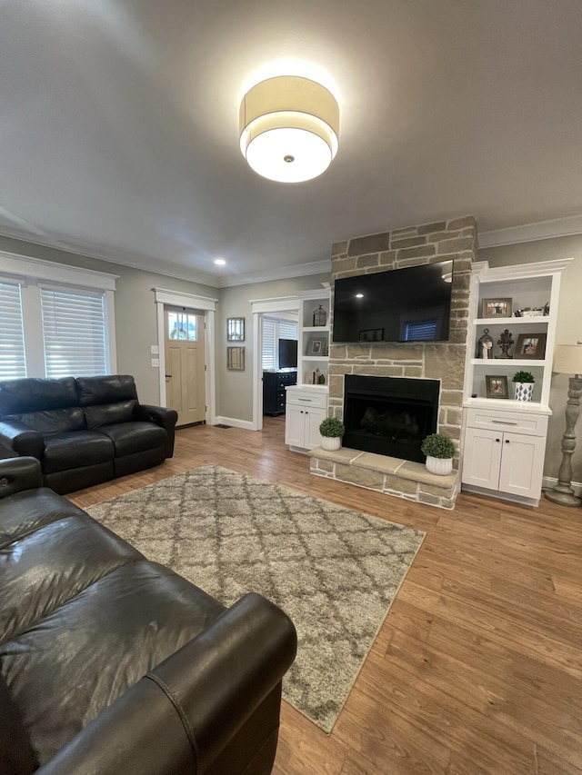 living room with ornamental molding, light wood-type flooring, a fireplace, and baseboards