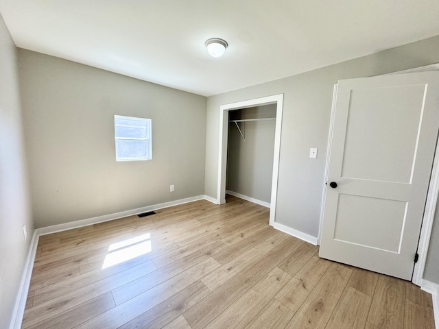 unfurnished bedroom featuring a closet, visible vents, light wood-type flooring, and baseboards