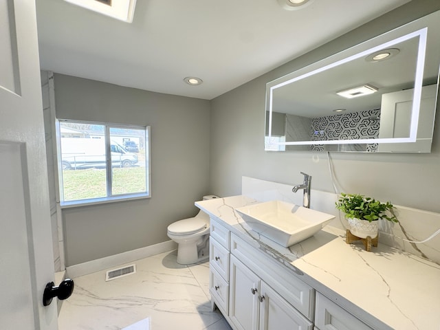 full bath with visible vents, toilet, marble finish floor, baseboards, and vanity