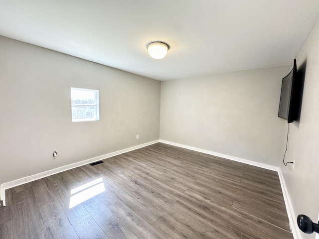 unfurnished room featuring visible vents, baseboards, and wood finished floors