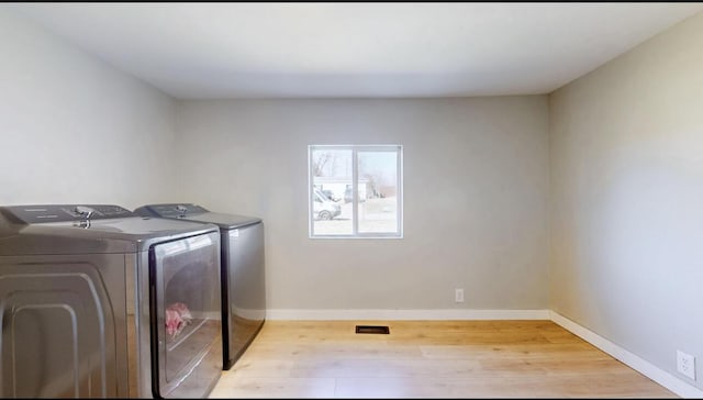 laundry area featuring visible vents, baseboards, laundry area, wood finished floors, and independent washer and dryer