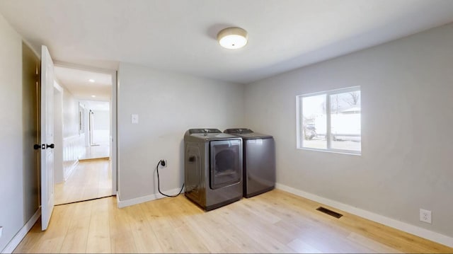 laundry area featuring washer and dryer, visible vents, baseboards, and light wood-style floors