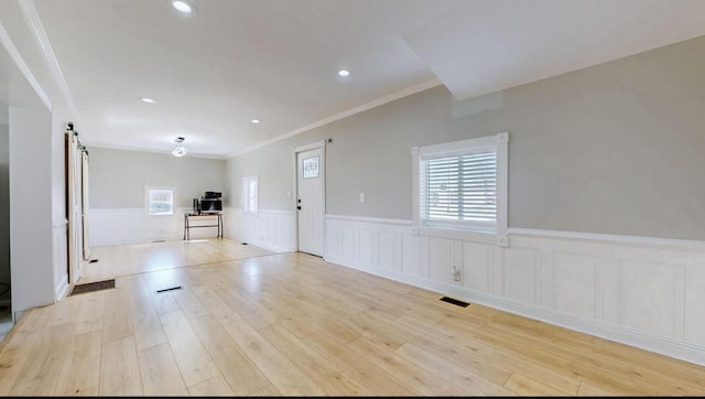 interior space with a wainscoted wall, visible vents, wood finished floors, recessed lighting, and a barn door