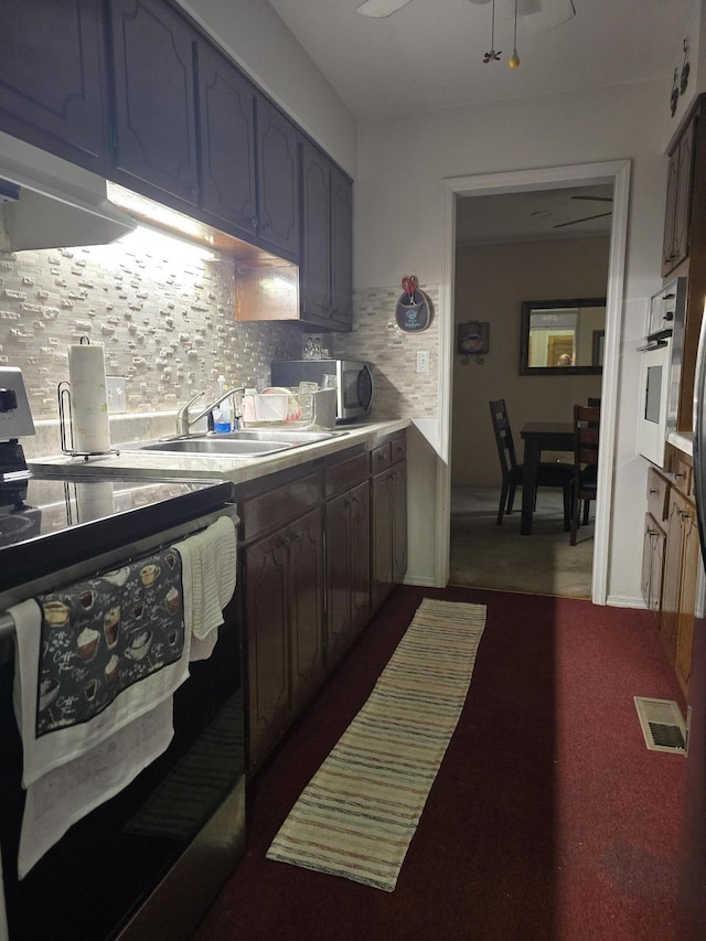 kitchen with white oven, stainless steel microwave, backsplash, electric range, and a sink