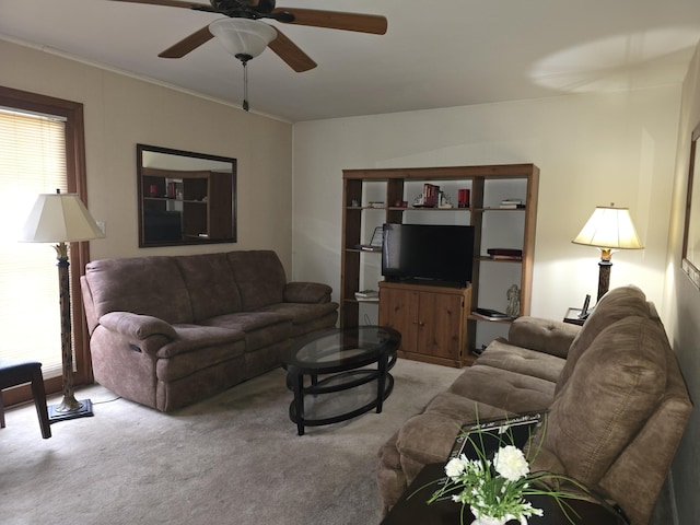 living area with a ceiling fan, light carpet, and crown molding