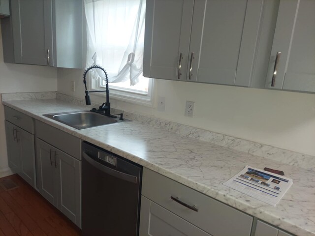 kitchen with dishwasher, dark wood-type flooring, light stone countertops, gray cabinetry, and a sink