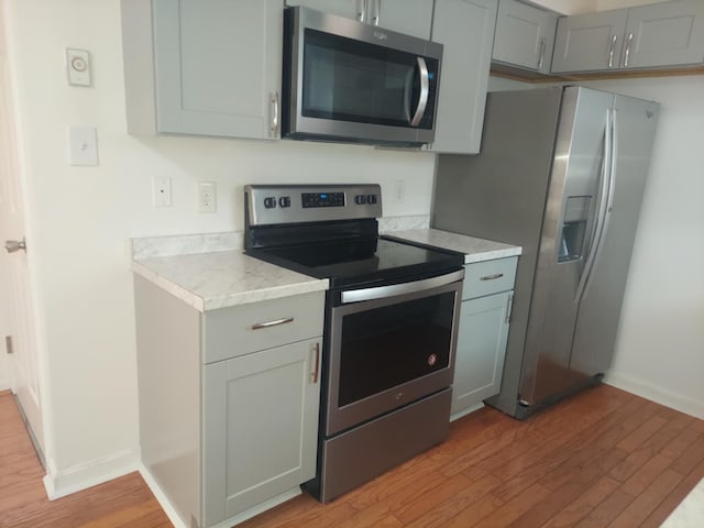 kitchen featuring stainless steel appliances, light wood-style flooring, and gray cabinetry