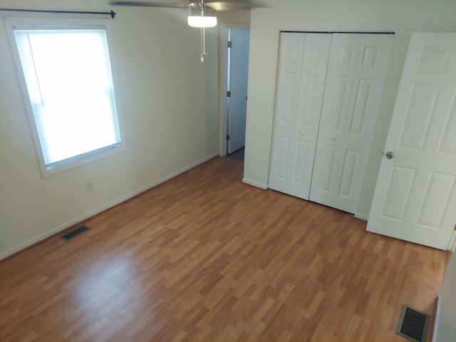 unfurnished bedroom with light wood finished floors, baseboards, visible vents, and a closet