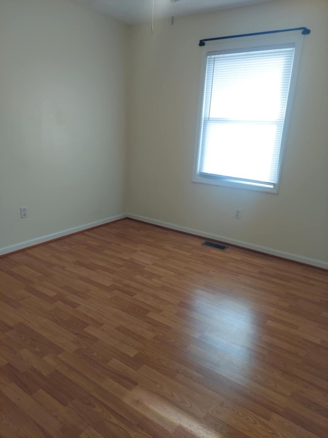 unfurnished room featuring visible vents, dark wood finished floors, and baseboards