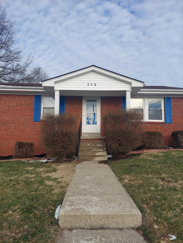 view of front facade featuring entry steps, brick siding, and a front yard