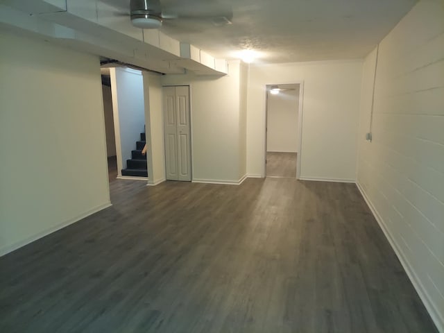 finished below grade area with baseboards, stairway, and dark wood-type flooring