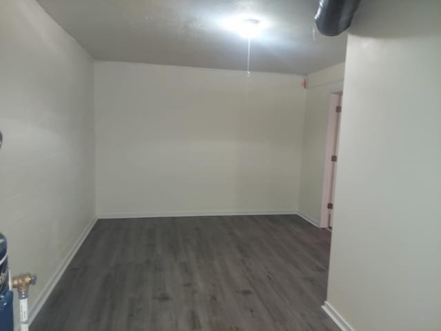 spare room featuring dark wood-style floors and baseboards