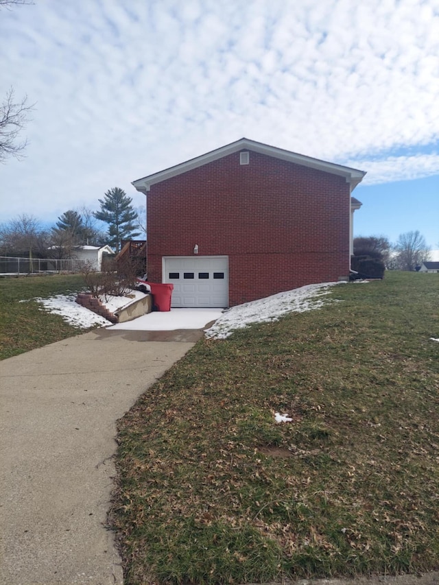 view of side of home with driveway, a yard, and brick siding