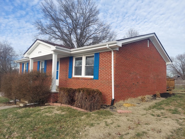 view of property exterior featuring brick siding and a lawn