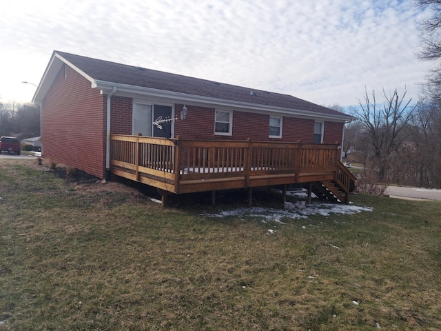 rear view of house with stairs, brick siding, a lawn, and a wooden deck