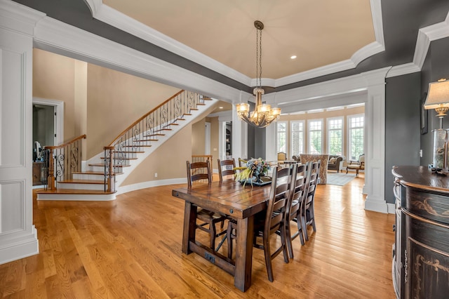 dining area featuring a tray ceiling, crown molding, stairway, a chandelier, and light wood-type flooring