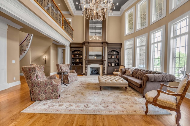 living room with a fireplace, crown molding, an inviting chandelier, wood finished floors, and baseboards